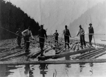 Les hommes debout sur les journaux dans la rivière.
